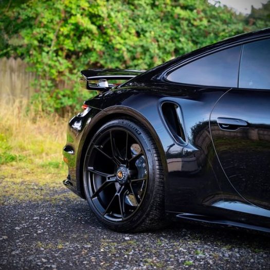 Close-up of gloss paintwork reflection on a black Porsche treated with ceramic coating.