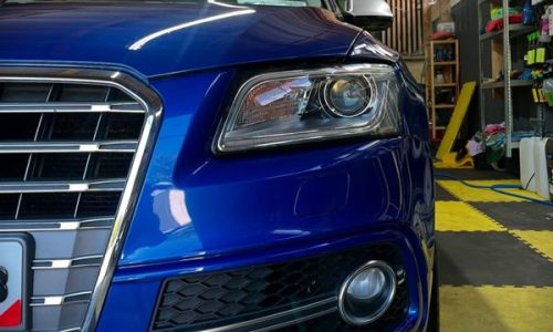 Close-up capture of the driver-side front bumper corner on a blue car, highlighting perfect defect removal on tight body contours for a Clane town driver.