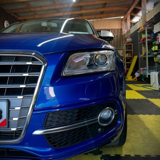 Close-up capture of the driver-side front bumper corner on a blue car, highlighting perfect defect removal on tight body contours for a Clane town driver.